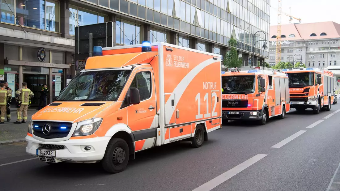 Einsatzfahrzeuge der Feuerwehr stehen vor dem mehrgeschossigen Gebäude, in dem es zu einem tödlichen Unfall mit einem Paternoster gekommen war. - Bild: Paul Zinken/dpa