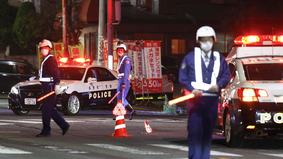 Polizisten stehen Wache auf einer Straße in der Nähe eines Gebäudes, in dem sich ein Mann verschanzt hat. - Foto: Takuto Kaneko/Kyodo News/AP/dpa