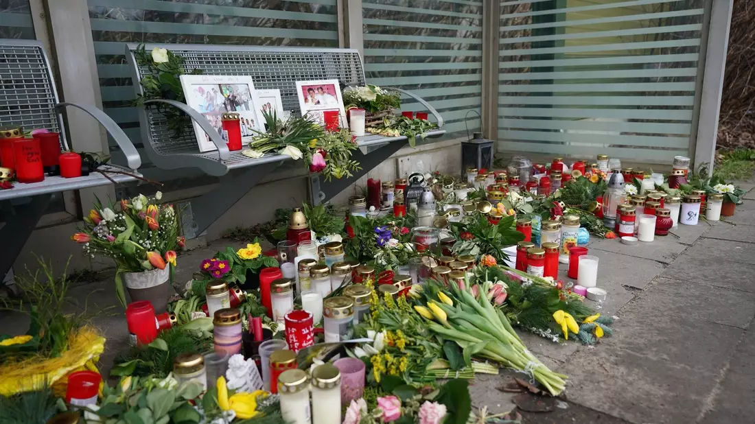 Kerzen und Blumen stehen und liegen im Bahnhof Brokstedt in einem Wartehäuschen. - Bild: Marcus Brandt/dpa