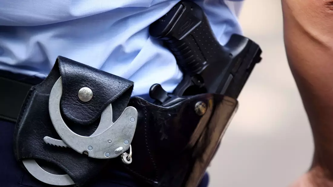 Ein Polizist trägt Handschellen bei sich: Die Bundespolizei hat mutmaßliche Schleuser festgenommen. - Bild: Oliver Berg/dpa/Symbolbild