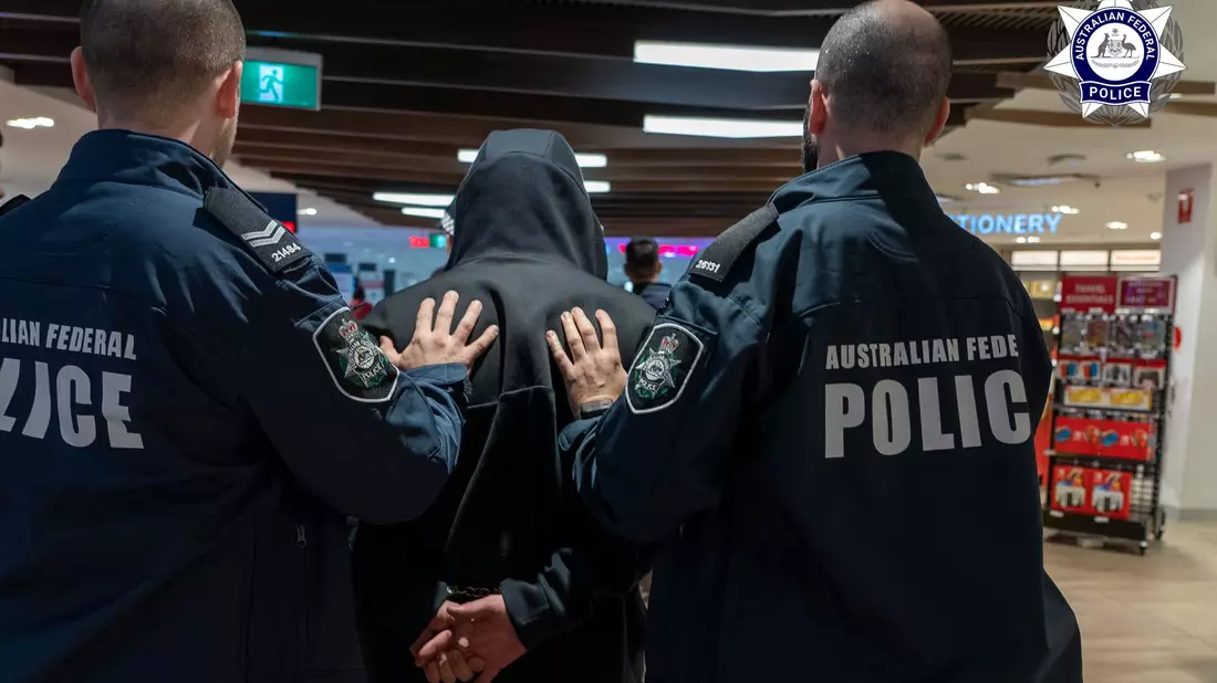 Polizisten führen den Schmuggler ab. - Bild: Supplied/Australian Federal Police AFP/AAP/dpa