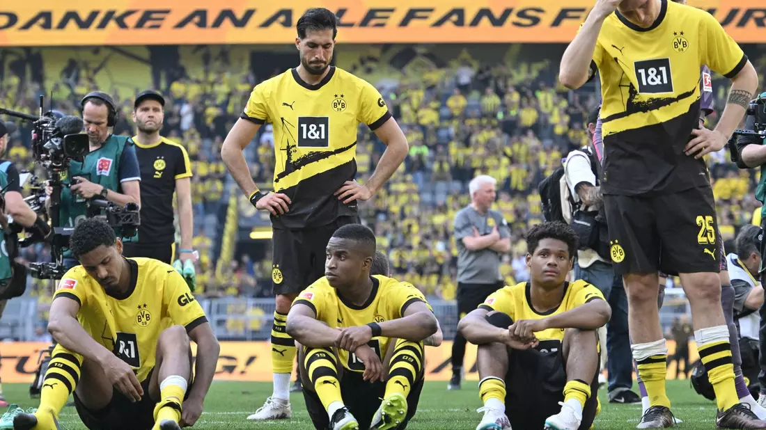 Spieler von Borussia Dortmund sitzen nach dem Spiel enttäuscht auf dem Platz. - Bild: Bernd Thissen/dpa