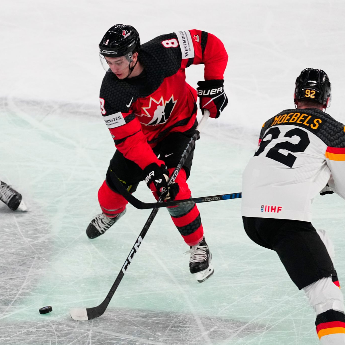 Kanadas Cody Glass (M) muss sich auf dem Eis gegen Marcel Noebels behaupten. - Foto: Pavel Golovkin/AP/dpa