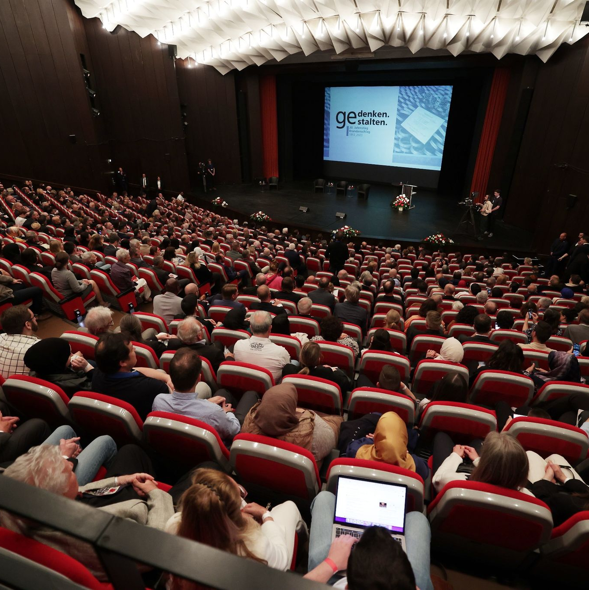 Gäste warten im Theater und Konzerthaus auf den Beginn der zentralen Gedenkfeier zum 30. Jahrestag des Solinger Brandanschlags. - Foto: David Young/dpa