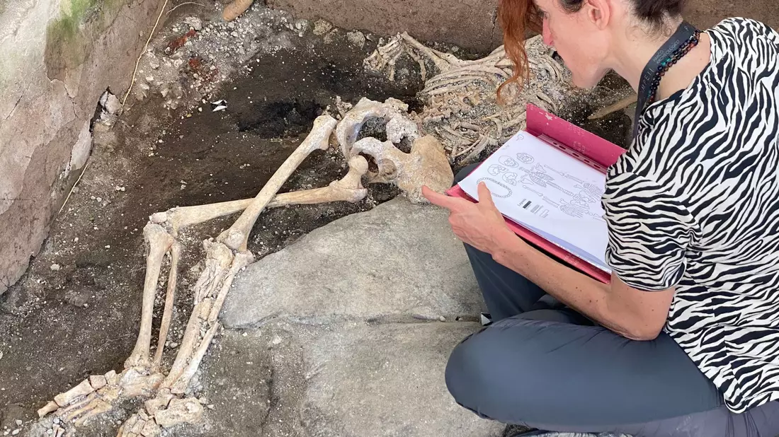 Eine Frau sitzt vor einem Skelett im Archäologiepark Pompeji. - Bild: -/Archäologiepark Pompeji/dpa