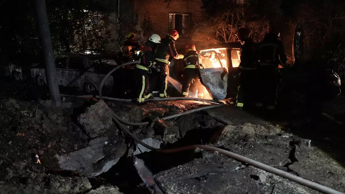 Rettungskräfte löschen in einem geparkten Auto ein Feuer, das nach einem russischen Luftangriff im Kiewer Pecherskyi-Viertel durch herabfallende Trümmer verursacht wurde. - Bild: Roman Hrytsyna/AP