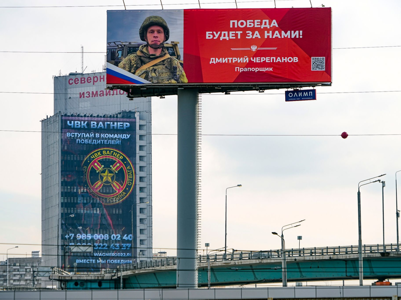 Ein Werbeschild, auf dem für das Militärunternehmen Wagner (hinten) geworben wird und auf dem zu lesen ist «Schließen Sie sich dem Team der Sieger an». - Foto: Alexander Zemlianichenko/AP/dpa