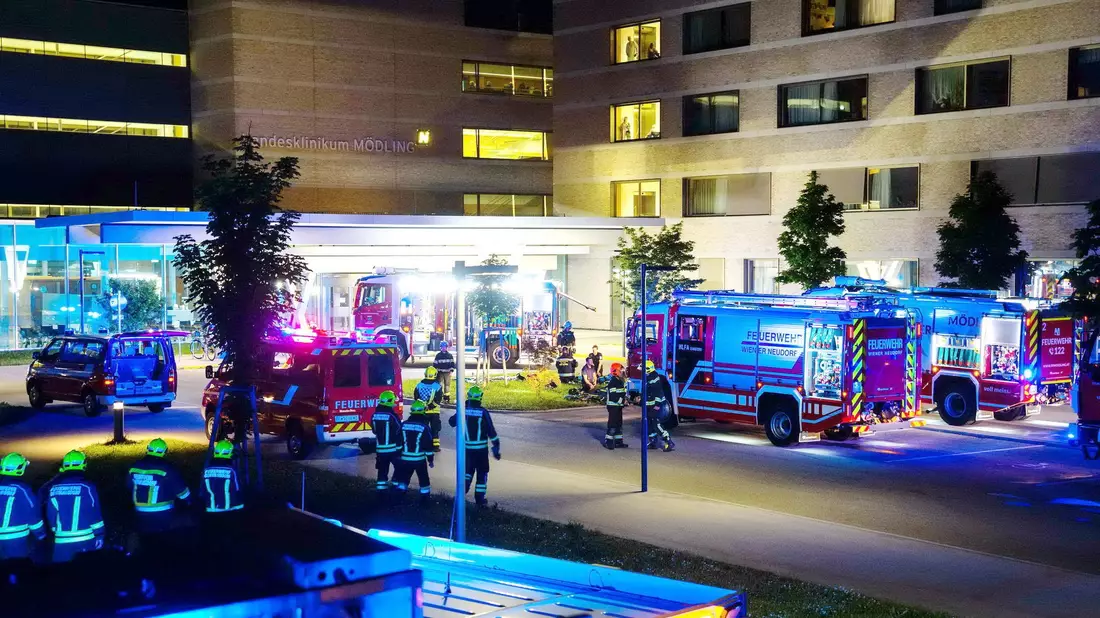 Feuerwehrfahrzeuge und Einsatzkräfte stehen vor dem Klinikum in Mödling. - Bild: Matthias Stur/PRESSESTELLE BFK MÖDLING/APA/dpa