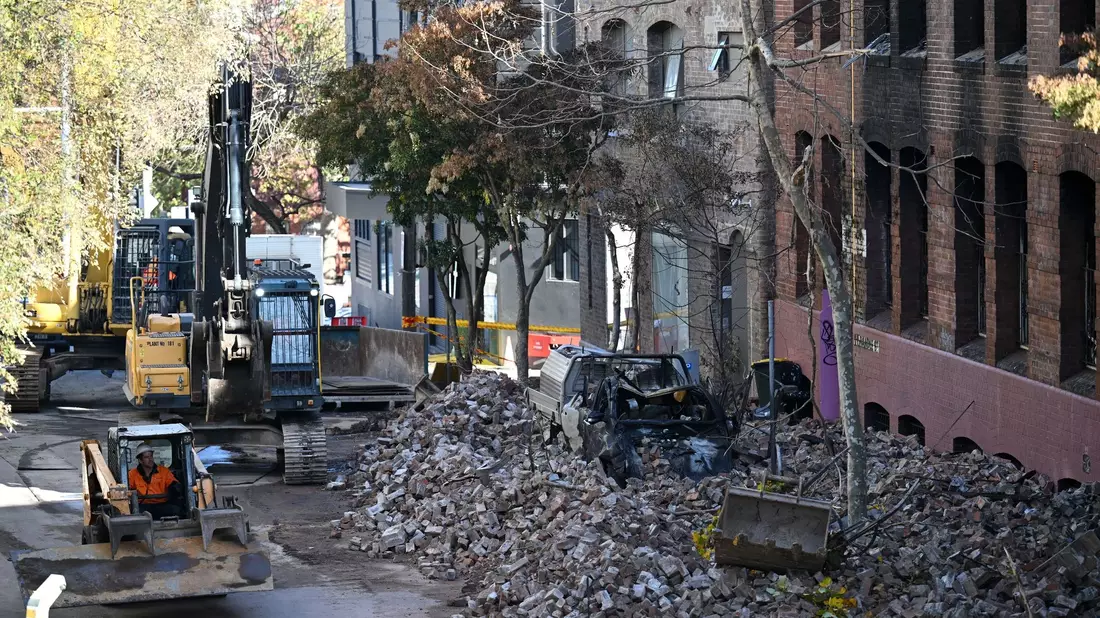 Arbeiter bereiten sich auf den Abriss der früheren Hutfabrik vor, die bei dem Brand in Sydney schwer beschädigt wurde. In dem leerstehenden Gebäude hatten vor dem Feuer Obdachlose Unterschlupf gefunden. - Bild: Dean Lewins/AAP/dpa