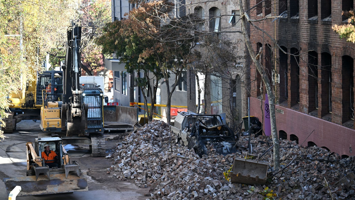 Arbeiter bereiten sich auf den Abriss der früheren Hutfabrik vor, die bei dem Brand in Sydney schwer beschädigt wurde. In dem leerstehenden Gebäude hatten vor dem Feuer Obdachlose Unterschlupf gefunden. - Foto: Dean Lewins/AAP/dpa