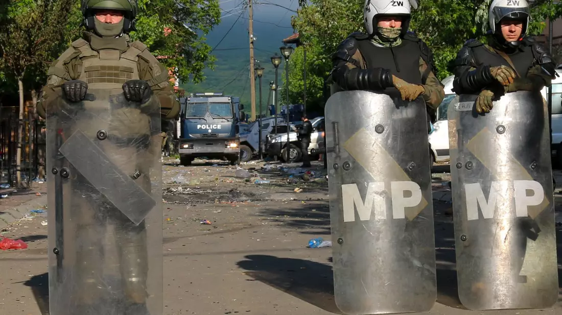 Soldaten und Polizisten bewachen nach den Zusammenstößen zwischen ethnischen Serben und Truppen der Nato-geführten KFOR-Friedenstruppe ein Gebäude in Zvecan. - Bild: Dejan Simicevic/AP