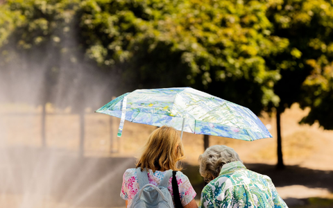 Zwei Frauen schützen mit einem Regenschirm vor der Sonne. - Foto: Rolf Vennenbernd/dpa