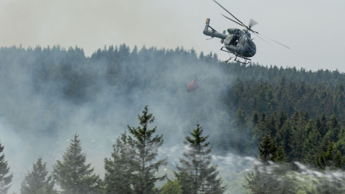 Die Feuerwehr versucht mit einem Hubschrauber einen Moorbrand im deutsch-belgischen Grenzgebiet bei Aachen zu löschen. - Foto: Ralf Roeger/dmp-press/dpa
