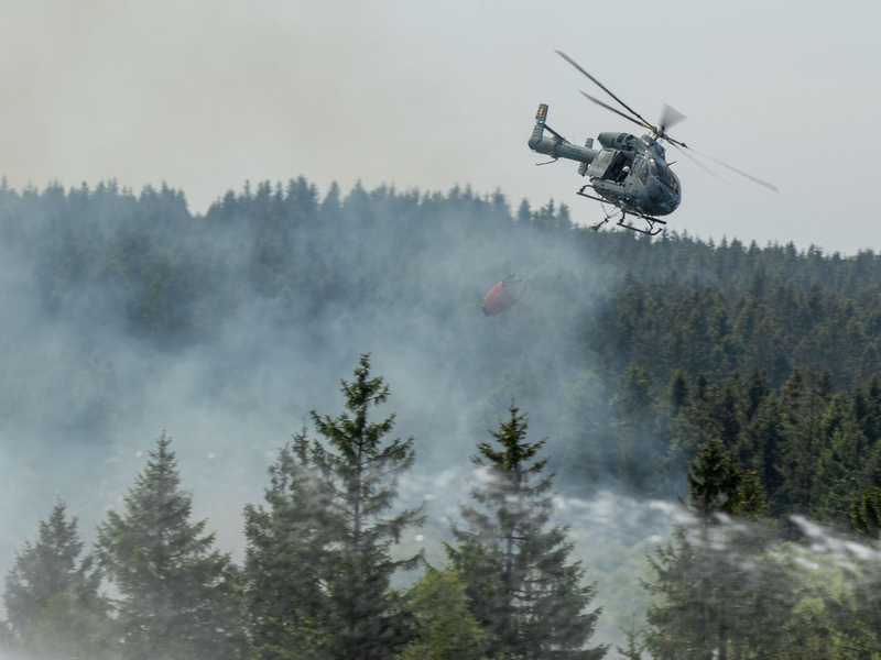 Die Feuerwehr versucht mit einem Hubschrauber einen Moorbrand im deutsch-belgischen Grenzgebiet bei Aachen zu löschen. - Foto: Ralf Roeger/dmp-press/dpa