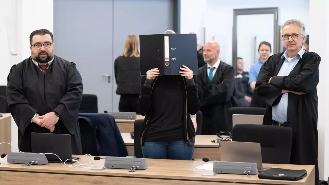 Die Angeklagte (M) steht bei der Fortsetzung des Prozesses im OLG Dresden im Verhandlungssaal. - Bild: Sebastian Kahnert/dpa