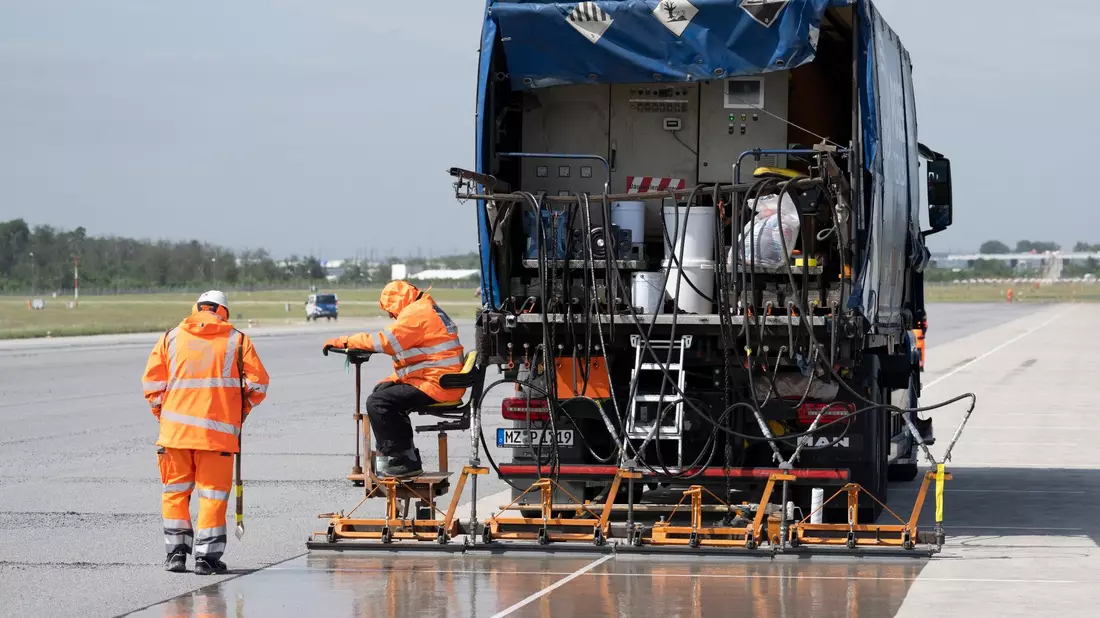 Eine spezielle Flüssig-Grundierung bringen Arbeiter mit einem Spezialfahrzeug auf der Landebahn Nordwest auf dem Flughafen in Frankfurt an. Am Frankfurter Flughafen hat der Betreiber Fraport die frisch sanierte Landebahn Nordwest nach wenigen Betriebsstunden wieder gesperrt. - Bild: Boris Roessler/dpa