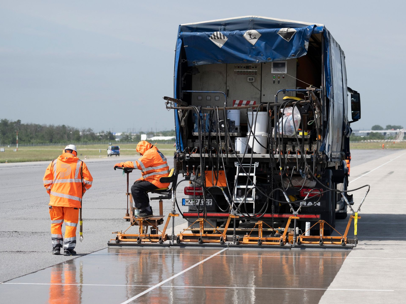 Eine spezielle Flüssig-Grundierung bringen Arbeiter mit einem Spezialfahrzeug auf der Landebahn Nordwest auf dem Flughafen in Frankfurt an. Am Frankfurter Flughafen hat der Betreiber Fraport die frisch sanierte Landebahn Nordwest nach wenigen Betriebsstunden wieder gesperrt. - Foto: Boris Roessler/dpa
