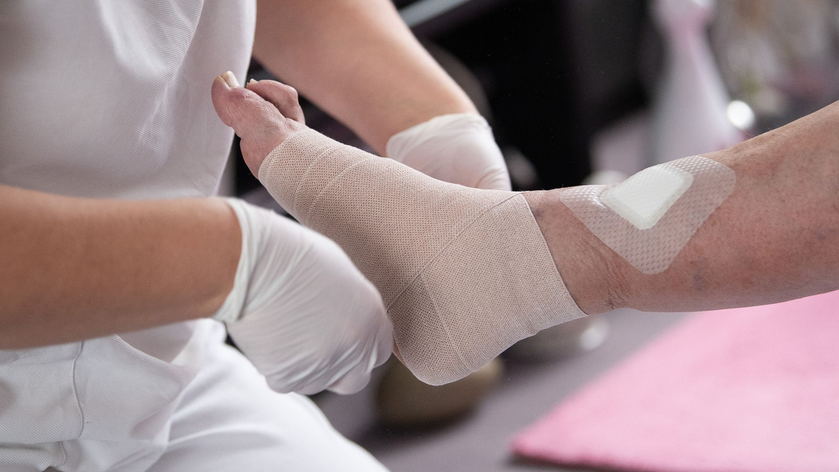 Eine Fachkraft in der ambulanten Pflege legt einen Kompressionsverband an. In der Pflegebranche herrscht Fachkräftemangel. - Foto: Sebastian Gollnow/dpa