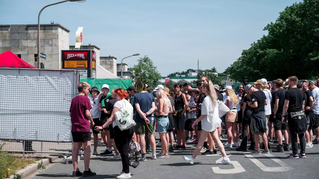 Besucherinnen und Besucher warten vor Beginn des Open-Air-Festivals Rock im Park auf den Einlass. - Bild: Daniel Vogl/dpa