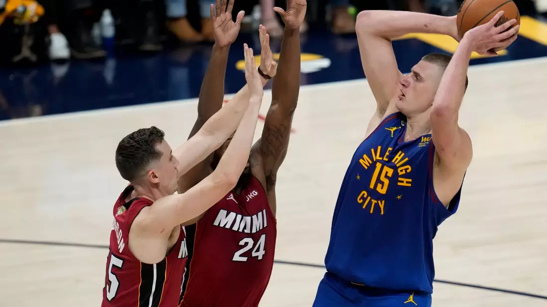 Denvers Nikola Jokic (r) wirft über Miamis Duncan Robinson (l) und Haywood Highsmith. - Bild: David Zalubowski/AP/dpa