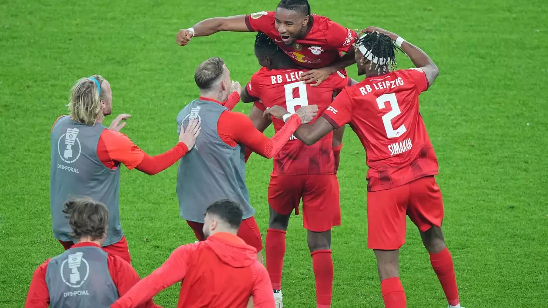 Leipziger Spieler stürmen nach dem Abpfiff auf Matchwinner Christopher Nkunku (M, oben) zu. - Bild: Sören Stache/dpa