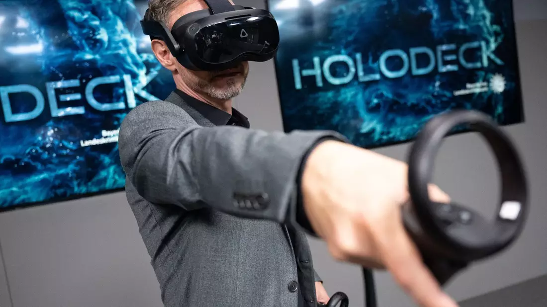 Ralf Breker, Leiter der forensischen Medientechnik beim LKA, steht mit einer VR-Brille während einer Pressekonferenz im Tatort-Virtual-Reality-Raum (Holodeck) des Bayerischen Landeskriminalamts (LKA). - Bild: Sven Hoppe/dpa