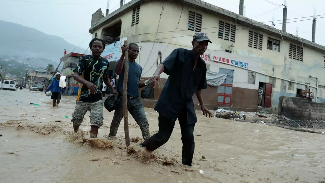 Bewohner waten über eine überschwemmte Straße nach einem starken Regen in Port-au-Prince. - Bild: Odelyn Joseph/AP