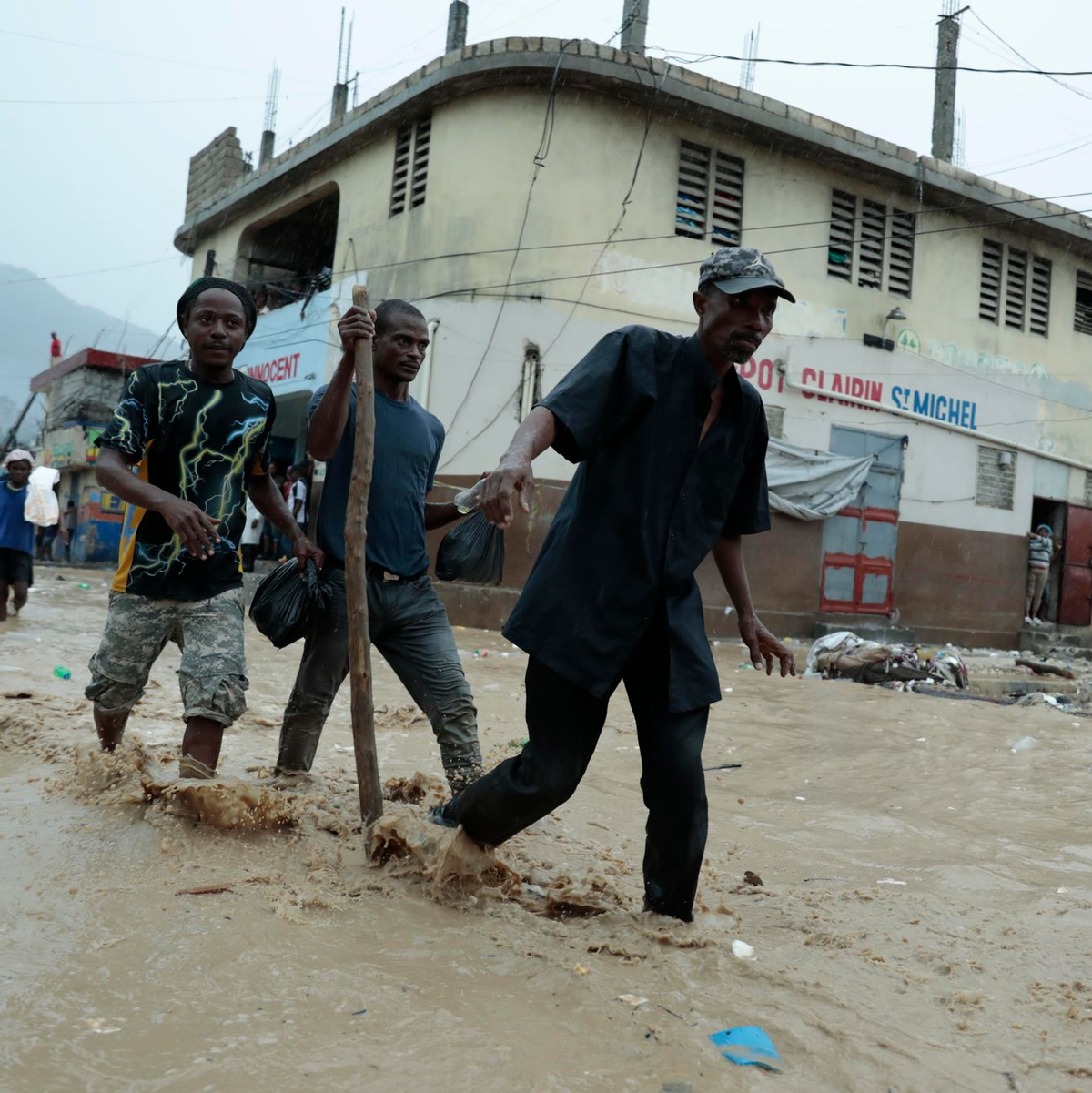 Bewohner waten über eine überschwemmte Straße nach einem starken Regen in Port-au-Prince. - Foto: Odelyn Joseph/AP