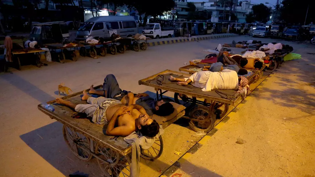 Arbeiter schlafen am Straßenrand an einem heißen Sommermorgen in Karatschi. - Bild: Fareed Khan/AP/dpa