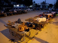 Verkäufer und Rikscha-Fahrer schlafen an einem heißen Sommermorgen im Freien. - Foto: Fareed Khan/AP/dpa