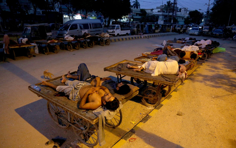 Arbeiter schlafen am Straßenrand an einem heißen Sommermorgen in Karatschi. - Foto: Fareed Khan/AP/dpa