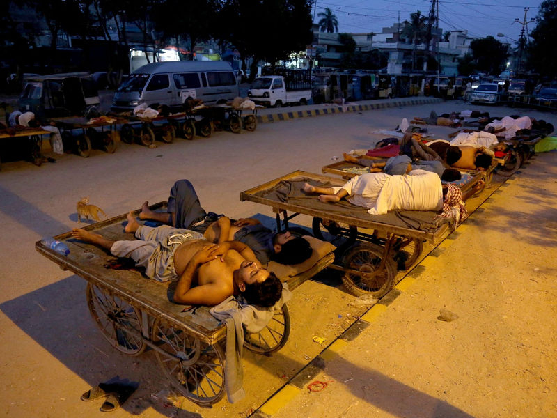 Arbeiter schlafen am Straßenrand an einem heißen Sommermorgen in Karatschi. - Foto: Fareed Khan/AP/dpa