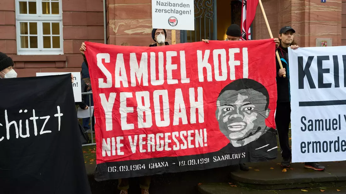 Der Asylbewerber Samuel Yeboah aus dem westafrikanischen Ghana wurde bei dem Anschlag getötet. Beim Auftakt des Prozesses 2022 machen Demonstranten darauf aufmerksam. - Bild: Thomas Frey/dpa