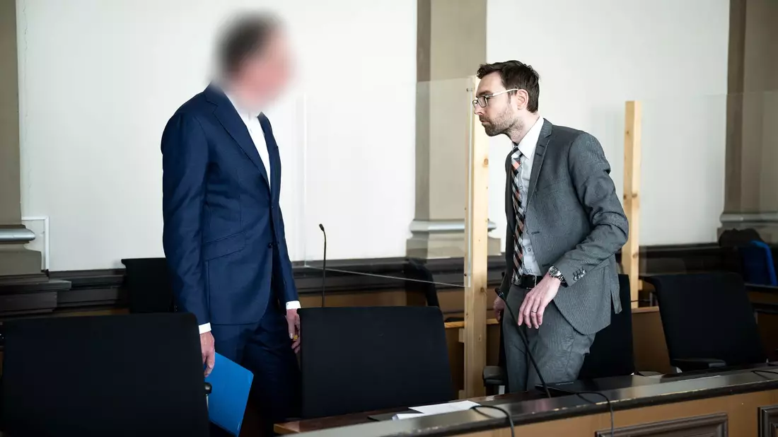 Der Angeklagte (l) steht vor Prozessbeginn mit seinem Anwalt im Gerichtssaal. - Bild: Sina Schuldt/dpa
