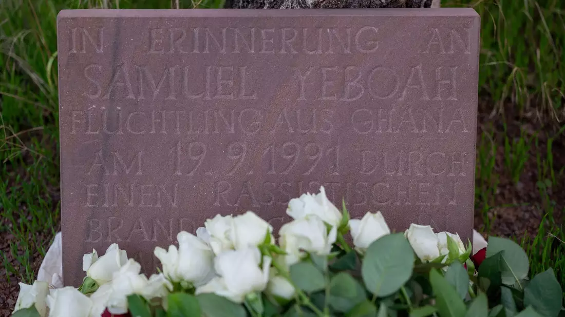 Teilnehmer der Gedenkkundgebung für den 1991 bei einem Brandanschlag getöteten ghanaischen Asylbewerber Samuel Yeboah haben an einem Gedenkstein Blumen abgelegt. - Bild: Harald Tittel/dpa