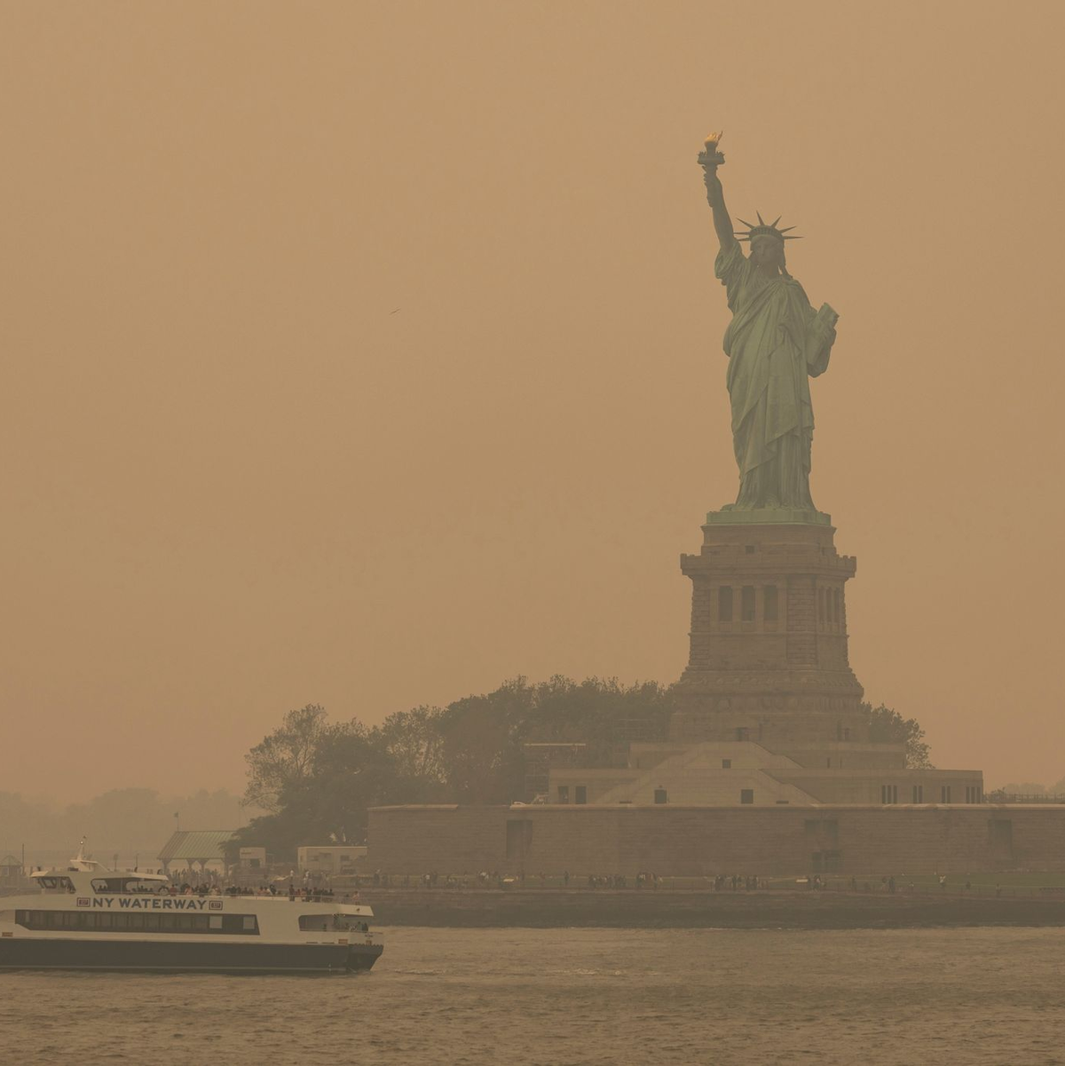 Die Freiheitsstatue ist in orangefarbenen Dunst gehüllt. - Foto: Yuki Iwamura/AP/dpa