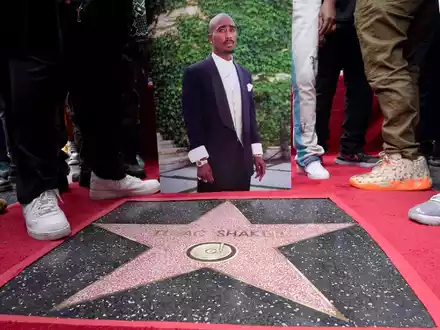 Ein Bild des verstorbenen Rappers und Schauspielers Tupac Shakur steht neben seinem Stern auf dem Hollywood Walk of Fame. - Foto: Chris Pizzello/Invision/AP/dpa