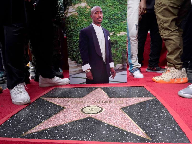 Ein Bild des verstorbenen Rappers und Schauspielers Tupac Shakur steht neben seinem Stern auf dem Hollywood Walk of Fame. - Foto: Chris Pizzello/Invision/AP/dpa