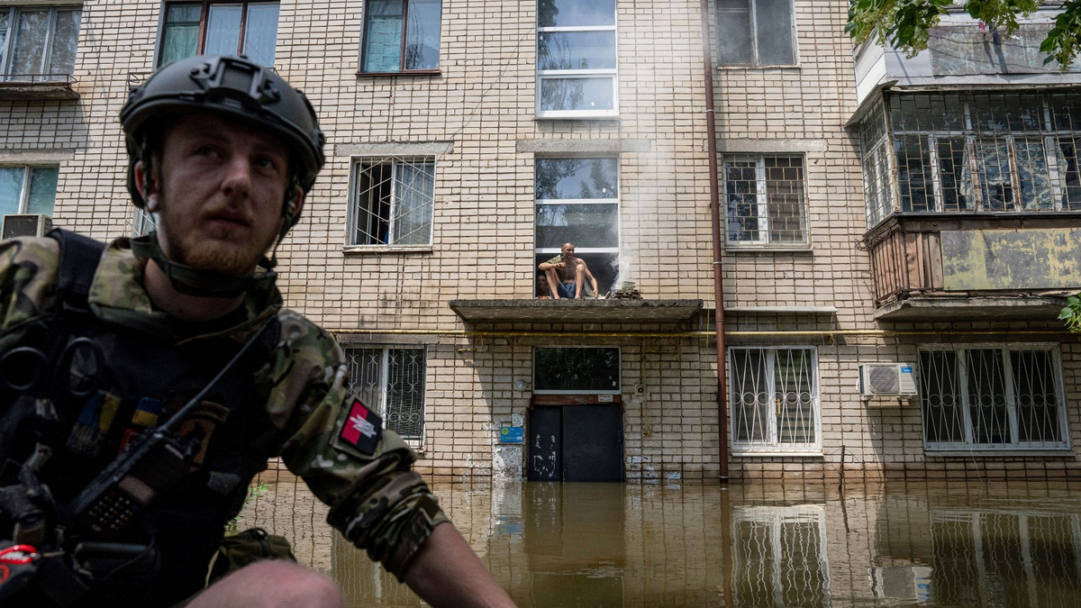 Ein Mann kocht auf einem offenen Feuer auf einer Veranda vor dem Eingang eines mehrstöckigen Gebäudes in einem überfluteten Viertel. - Foto: Evgeniy Maloletka/AP/dpa