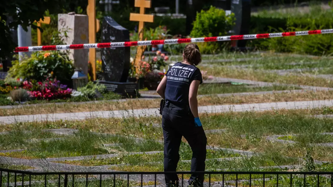 Die Polizei am Tatort auf einem Friedhof. - Bild: Christoph Schmidt/dpa