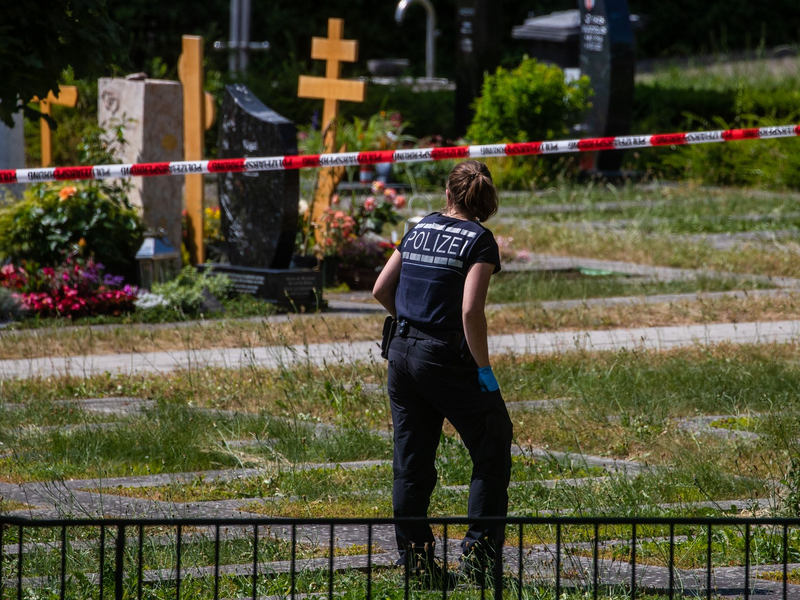 Eine Mitarbeiterin der Spurensicherung vermisst Spuren am Tatort auf einem Friedhof. - Foto: Christoph Schmidt/dpa