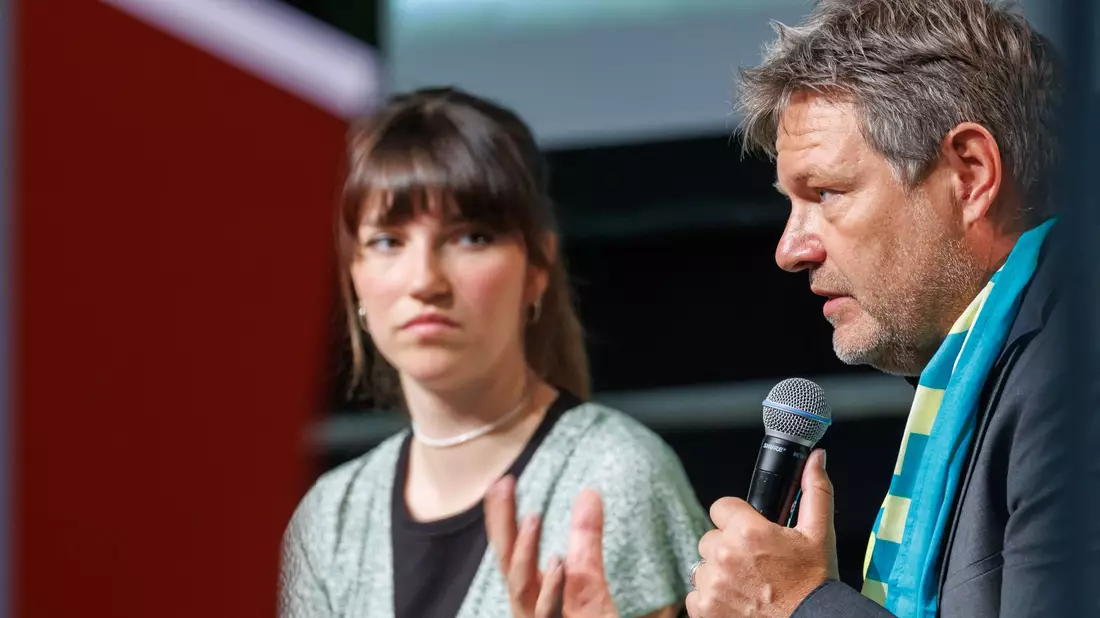 Wirtschaftsminister Robert Habeck und die Sprecherin der Letzten Generation, Carla Hinrichs, nehmen gemeinsam an einer Podiumsdikussion teil. - Bild: Daniel Karmann/dpa