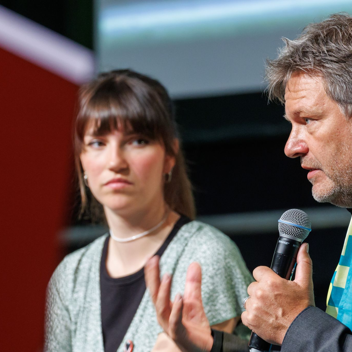 Wirtschaftsminister Robert Habeck und die Sprecherin der Letzten Generation, Carla Hinrichs, nehmen gemeinsam an einer Podiumsdikussion teil. - Foto: Daniel Karmann/dpa