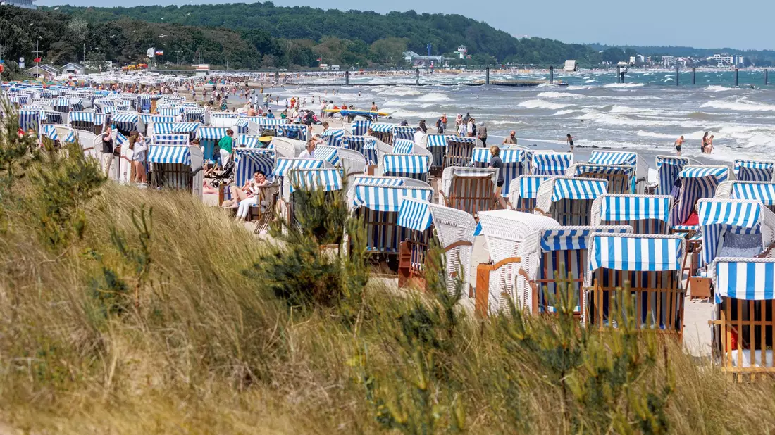 Bei Sonnenschein und starkem Wellengang ist die Wasserkante von Timmendorfer Strand gut besucht. - Bild: Markus Scholz/dpa