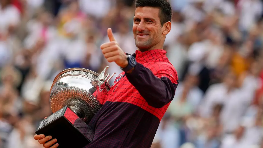 Novak Djokovic freut sich mit der Trophäe über den Sieg bei den French Open. - Bild: Thibault Camus/AP/dpa