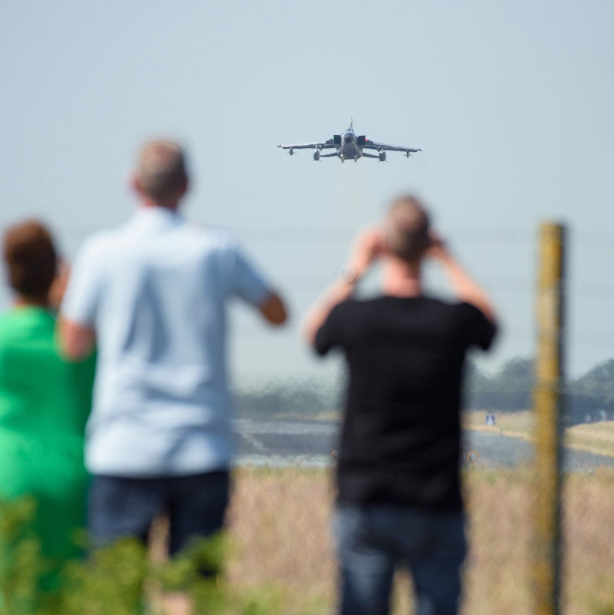 Schaulustige beobachten den Start eines Tornado-Kampfjets zu Beginn des internationalen Luftwaffen-Manövers «Air Defender 2023» am Zaun des Fliegerhorst Schleswig/Jagel. - Foto: Gregor Fischer/dpa