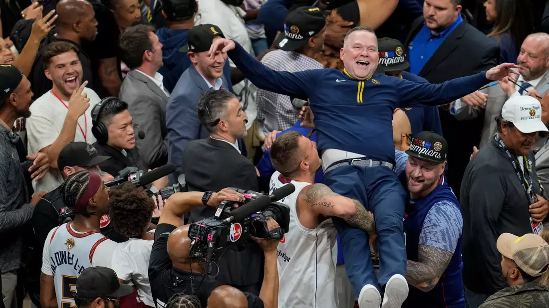 Michael Malone, Cheftrainer der Denver Nuggets, wird von den Fans hochgehoben, nachdem das Team die NBA-Meisterschaft gewonnen hat. - Bild: David Zalubowski/AP
