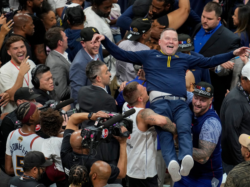Michael Malone, Cheftrainer der Denver Nuggets, wird von den Fans hochgehoben, nachdem das Team die NBA-Meisterschaft gewonnen hat. - Foto: David Zalubowski/AP