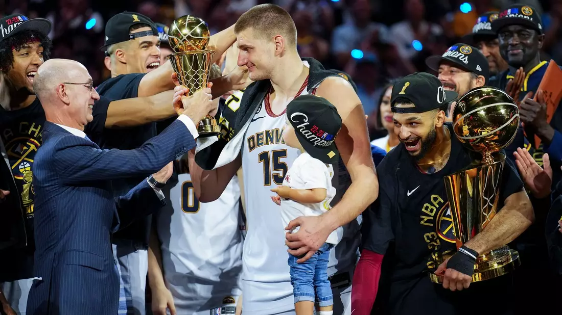 NBA-Commissioner Adam Silver (l) überreicht die MVP-Trophäe an Nuggets-Center Nikola Jokic (M.). - Bild: Jack Dempsey/AP/dpa