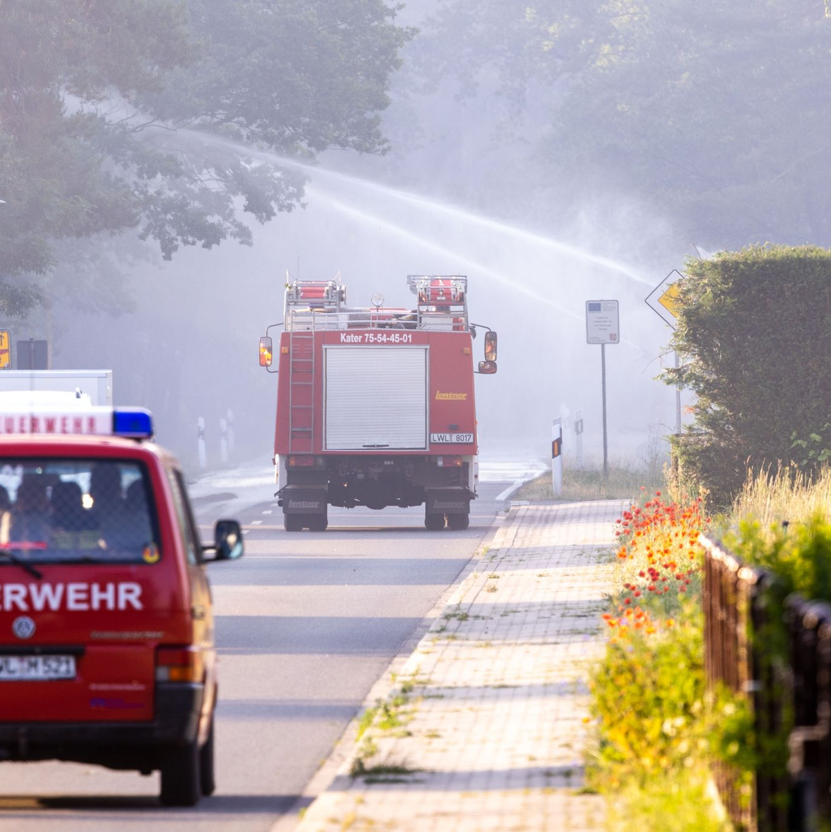 Feuerwehrfahrzeuge in der evakuierten Ortschaft Volzrade, durch die Rauch vom Waldbrand auf dem ehemaligen Truppenübungsplatz zieht. - Foto: Jens Büttner/dpa